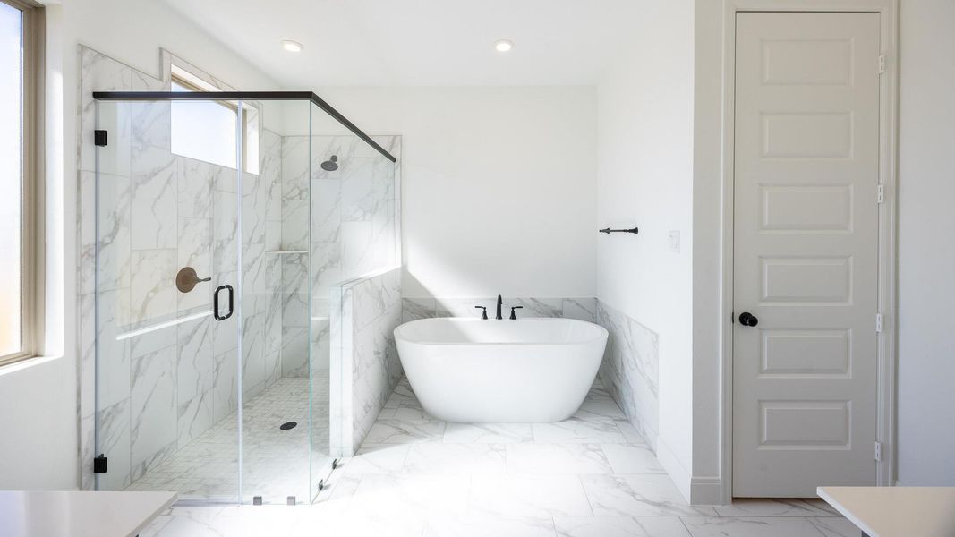 Bathroom with a freestanding bath, a marble finish shower, a wainscoted wall, tile walls, and marble finish flooring Bathroom with a freestanding bath, a marble finish shower, a wainscoted wall, tile walls, and marble finish flooring