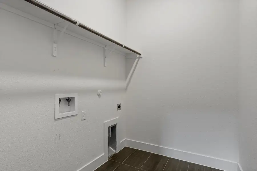 Ready for your appliances, this dedicated laundry room features functional shelving and a tiled floor.