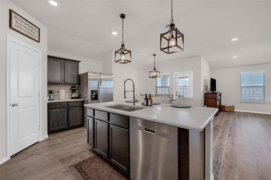 Kitchen with stainless steel appliances, light wood finished floors, light countertops, backsplash, and recessed lighting