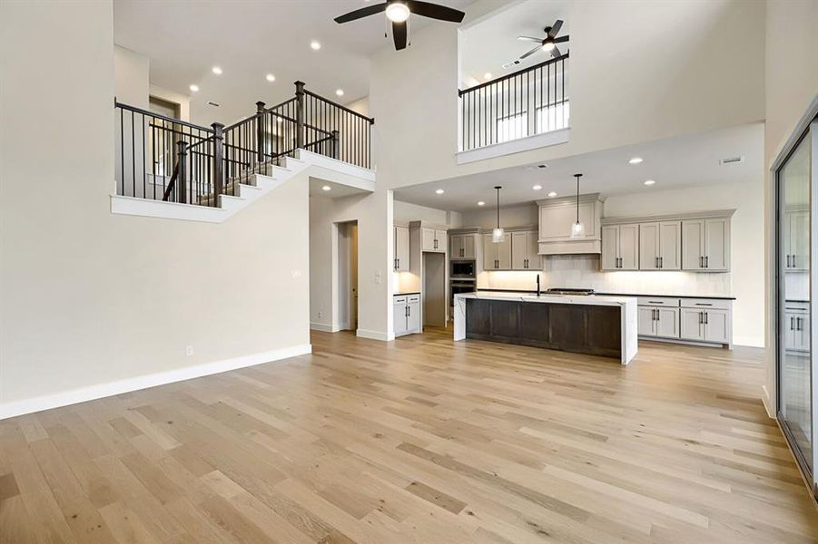 Kitchen with open floor plan, ceiling fan, an island with sink, a high ceiling, and stainless steel appliances Kitchen with open floor plan, ceiling fan, an island with sink, a high ceiling, and stainless steel appliances