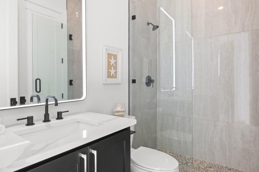 The full main floor guest bath can be accessed via the hallway and guest room and comes with a gorgeous frameless walk-in shower and luxury finishes.