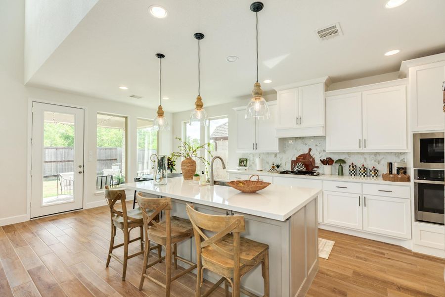 This gourmet kitchen features elegant quartz countertops, recessed lighting, an abundance of natural light from large windows, and modern pendant lights situated over the breakfast bar. This gourmet kitchen features elegant quartz countertops, recessed lighting, an abundance of natural light from large windows, and modern pendant lights situated over the breakfast bar.