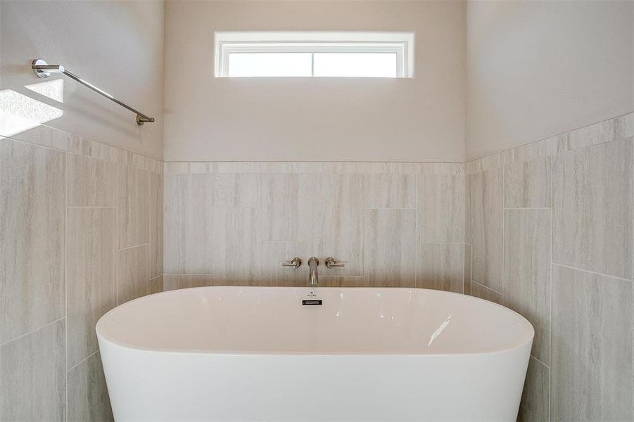 Bathroom featuring tile walls and a tub