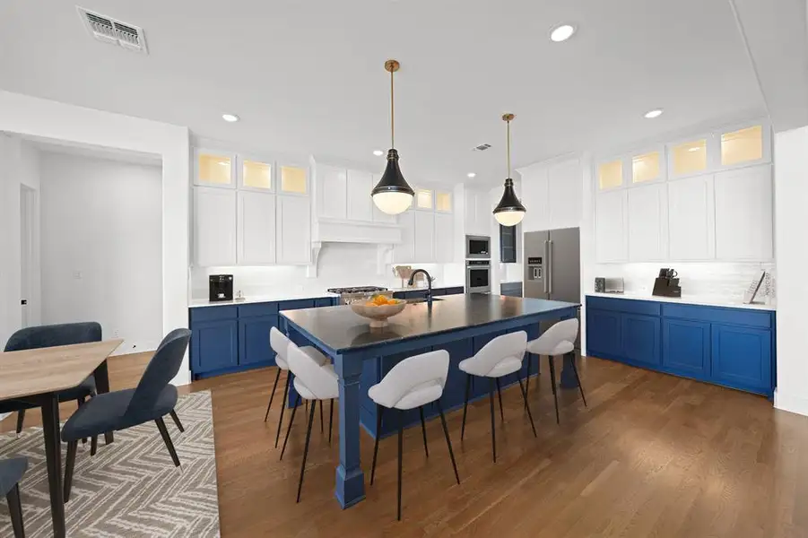 Kitchen with blue cabinetry, glass insert cabinets, white cabinets, a breakfast bar area, and decorative light fixtures Kitchen with blue cabinetry, glass insert cabinets, white cabinets, a breakfast bar area, and decorative light fixtures