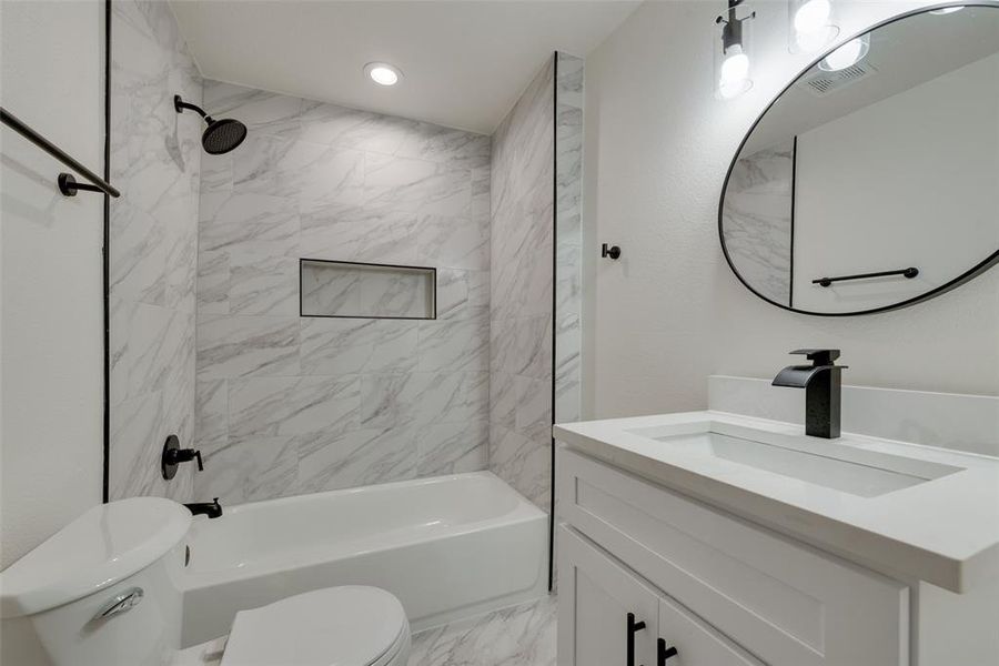 Full bathroom with tile flooring, tiled shower / bath combo, vanity, and toilet