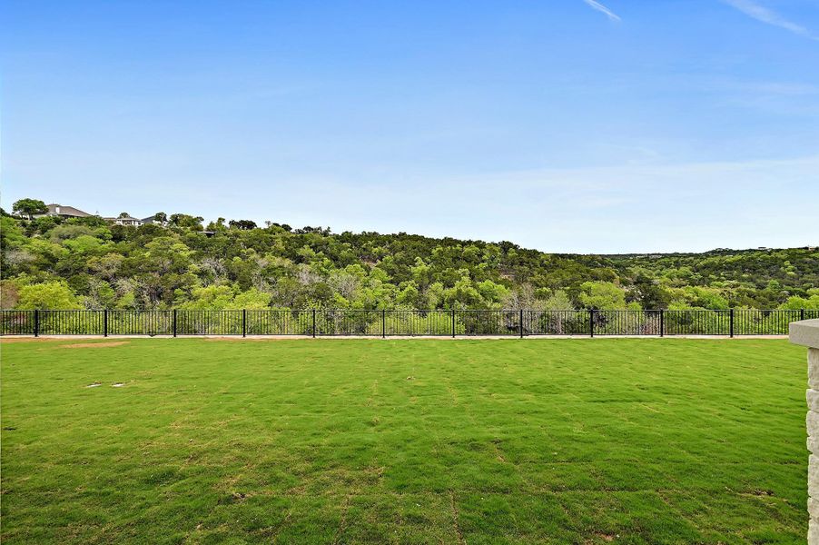 Green space stretches towards a scenic, tree-lined hillside and canyon. Backyard was designed for a future pool.