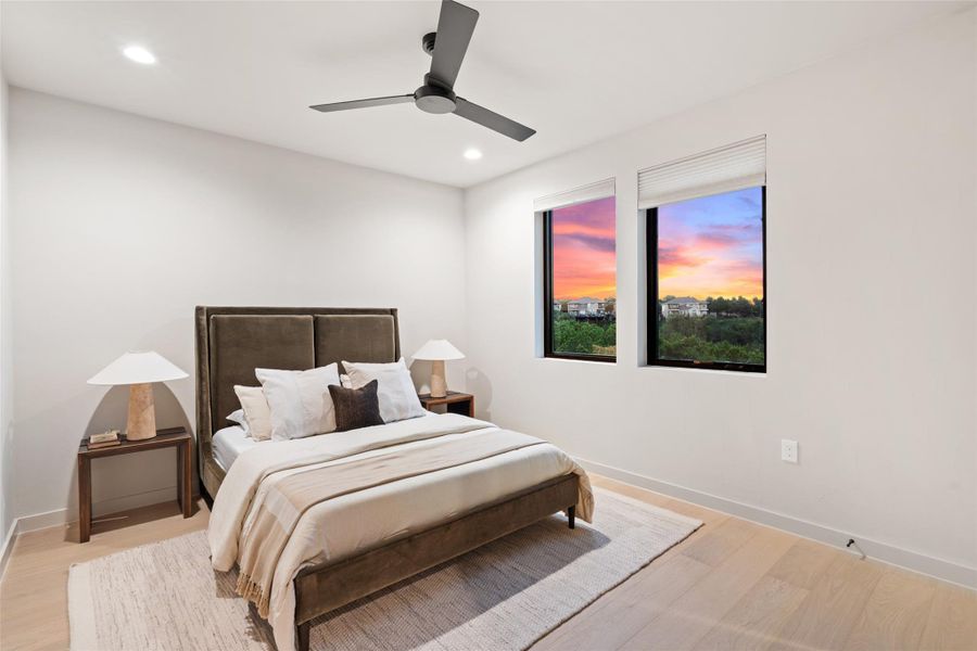 Recessed lighting and a sleek ceiling fan illuminate this inviting bedroom, offering picturesque views of a colorful sunset. Recessed lighting and a sleek ceiling fan illuminate this inviting bedroom, offering picturesque views of a colorful sunset.