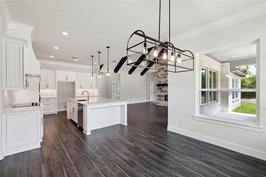 Kitchen with decorative light fixtures, white cabinetry, sink, a kitchen island with sink, and dark wood-type flooring