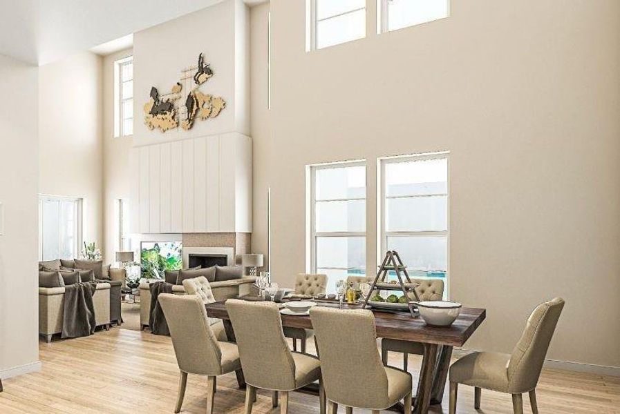 Dining space featuring a fireplace, light wood-type flooring, a towering ceiling, and plenty of natural light Dining space featuring a fireplace, light wood-type flooring, a towering ceiling, and plenty of natural light
