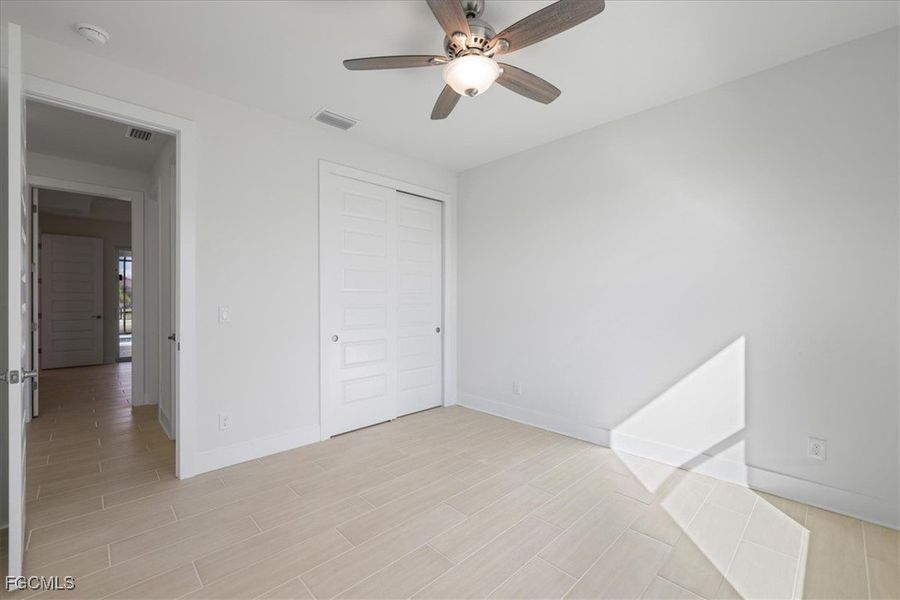 Unfurnished bedroom featuring wood finish floors, a ceiling fan, and a closet