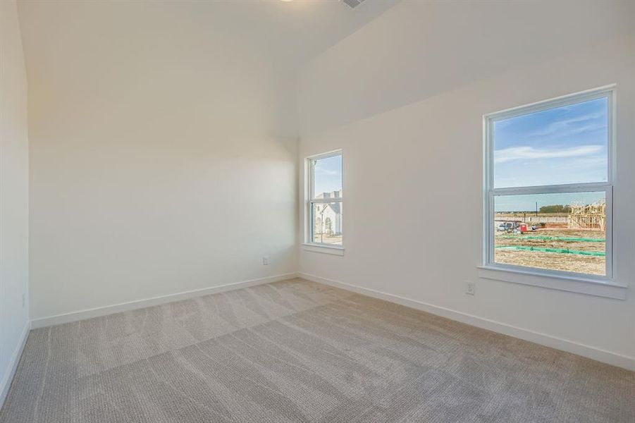 Unfurnished room with light colored carpet and vaulted ceiling Unfurnished room with light colored carpet and vaulted ceiling