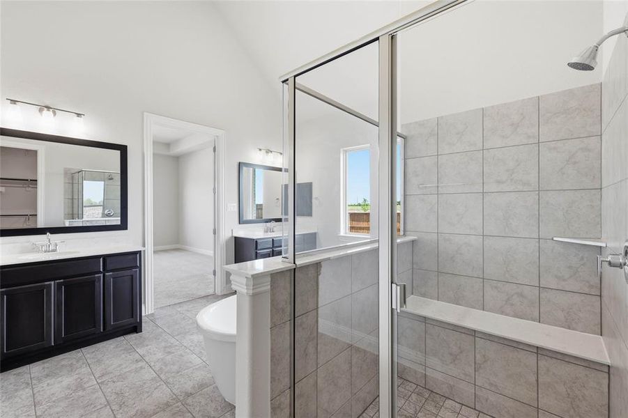Bathroom featuring a stall shower, a soaking tub, two vanities, and light tile patterned floors Bathroom featuring a stall shower, a soaking tub, two vanities, and light tile patterned floors