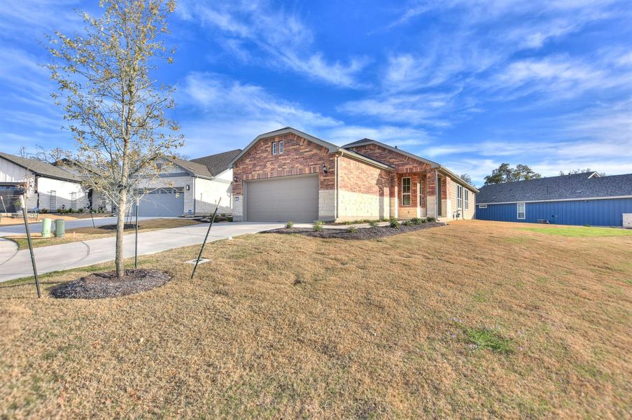 Single story home with brick siding, an attached garage, concrete driveway, and a front lawn