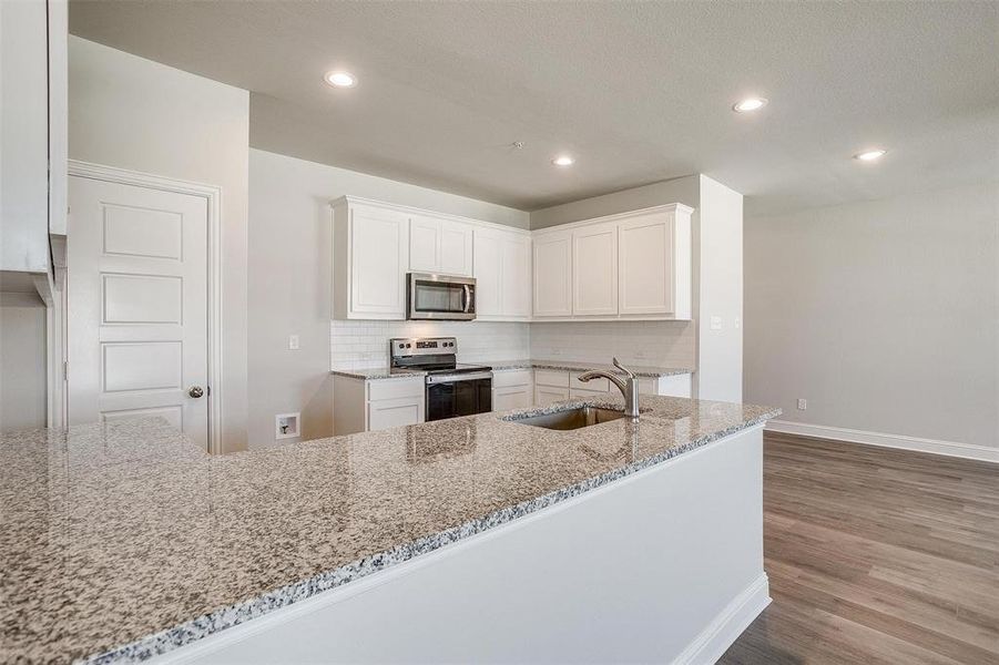 Kitchen featuring white cabinetry, stainless steel appliances, dark wood-style floors, light stone counters, and backsplash