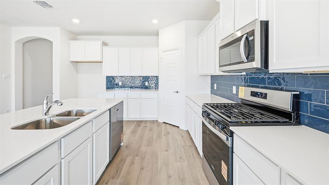 Kitchen featuring stainless steel appliances, light wood-style floors, white cabinets, backsplash, and recessed lighting