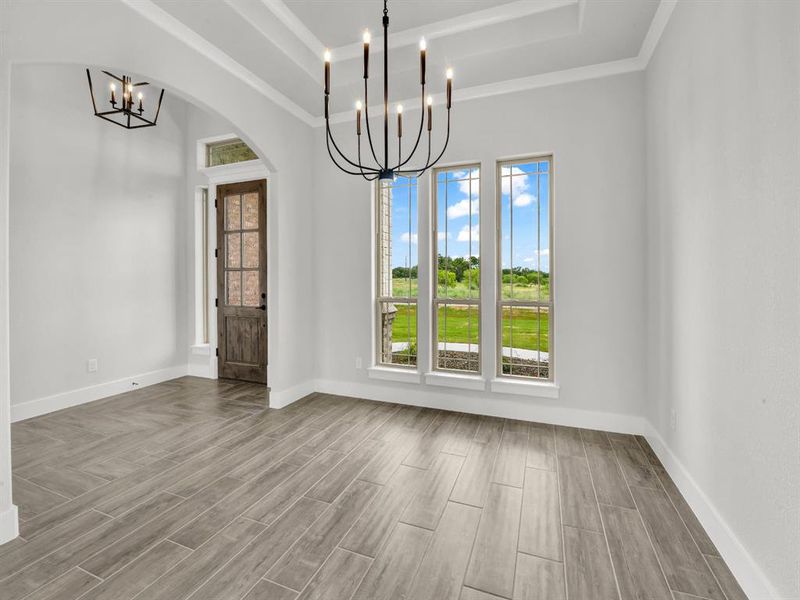 Unfurnished dining area with a chandelier, wood tiled floors, arched walkways, and a tray ceiling
