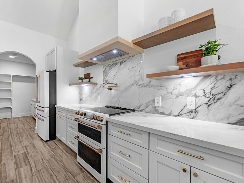 Your spacious kitchen looks amazing! Featuring luxury cafe appliances, gold hardware and a pot filler this is truly a dream.