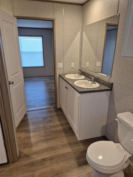 Full bath with double vanity and dark wood-style floors