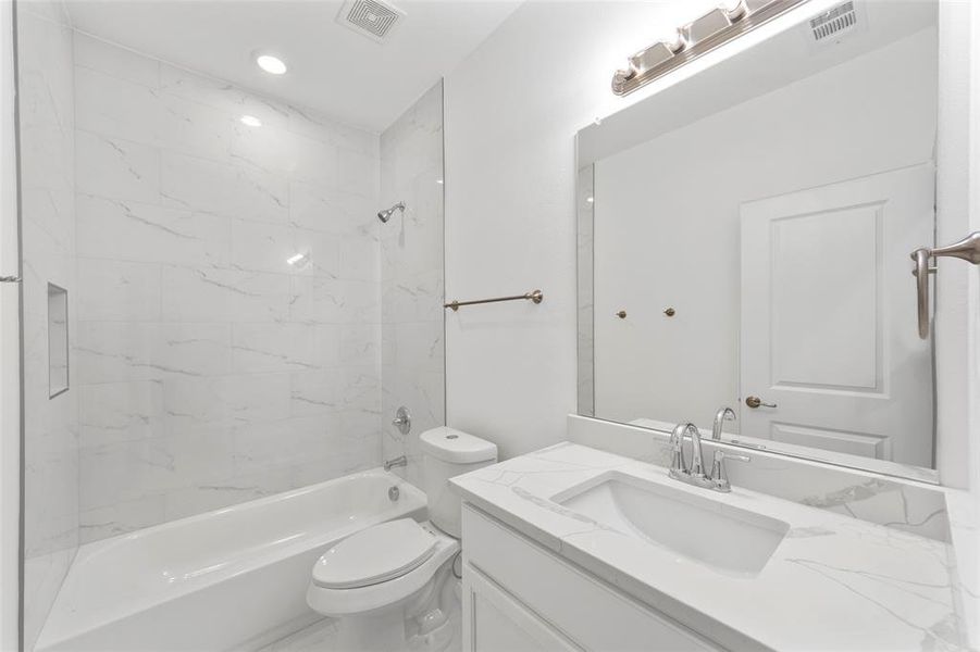 Full bathroom with tiled shower / bath, vanity, and toilet