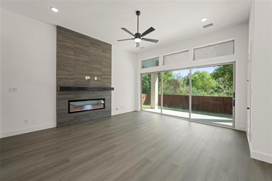 Unfurnished living room with ceiling fan, a large fireplace, dark wood finished floors, and recessed lighting