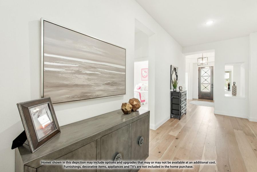 Hallway with light hardwood floors, white walls, gray console table, and front door with glass panels visible at end