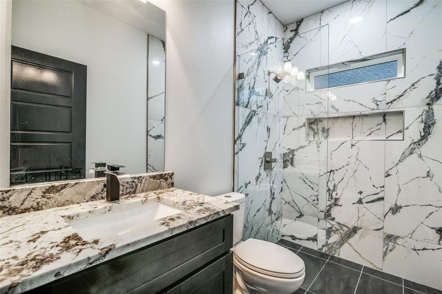 Bathroom with toilet, vanity, and a tile shower