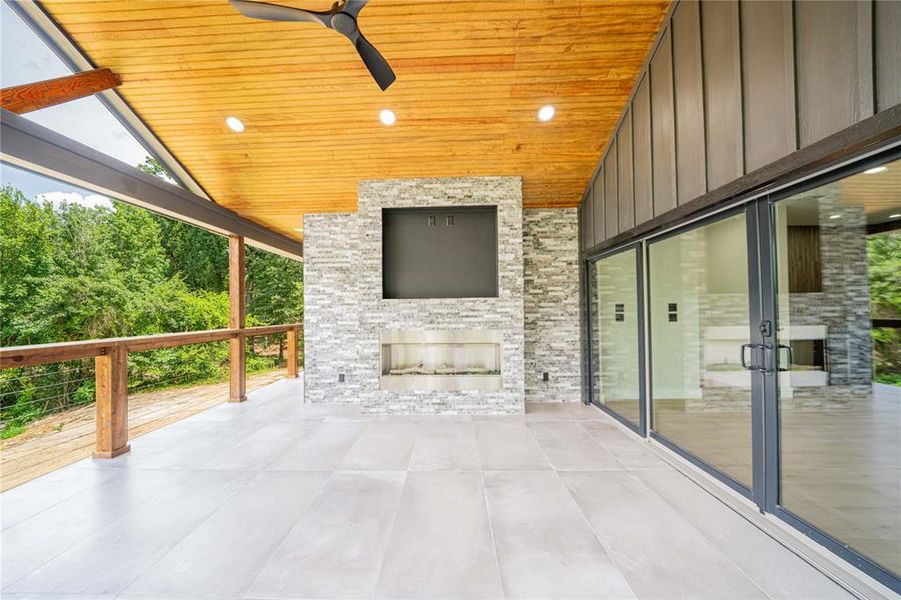 Spacious covered outdoor living area featuring a wood-finish ceiling, recessed lighting, and a modern ceiling fan