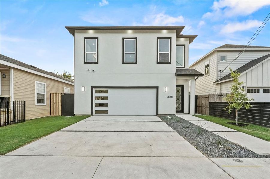 Contemporary house featuring a garage and a front lawn