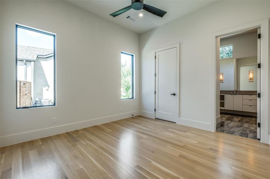 Unfurnished bedroom featuring ceiling fan, sink, light wood-type flooring, and multiple windows