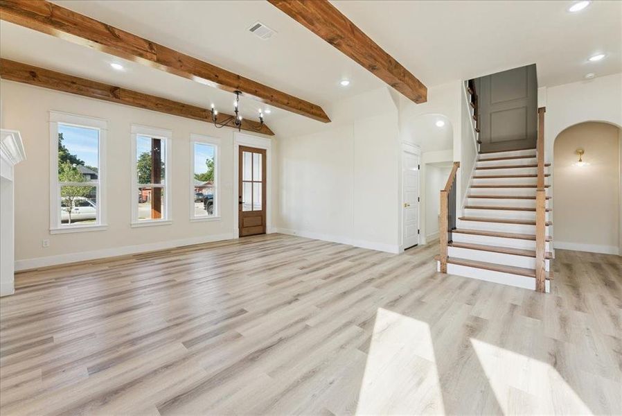 Unfurnished living room featuring arched walkways, stairway, recessed lighting, light wood-type flooring, and a chandelier
