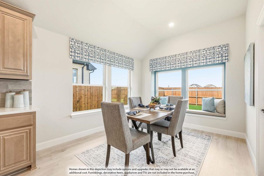 Dining area with wood table, four chairs, window seat, and large windows with patterned valances on light hardwood floors