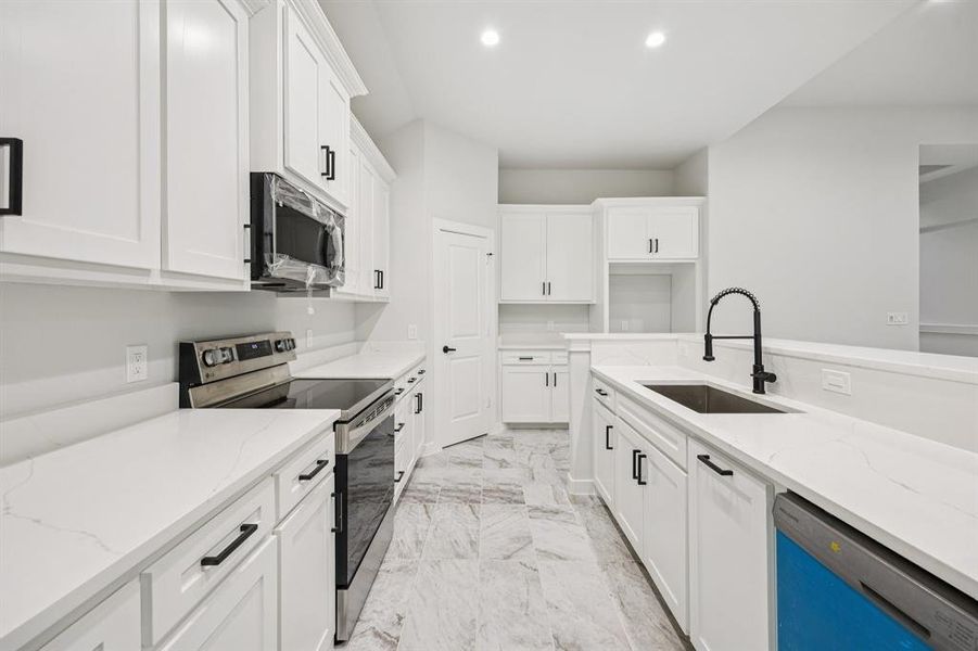 Kitchen featuring appliances with stainless steel finishes, light marble finish flooring, white cabinets, recessed lighting, and light stone countertops Kitchen featuring appliances with stainless steel finishes, light marble finish flooring, white cabinets, recessed lighting, and light stone countertops