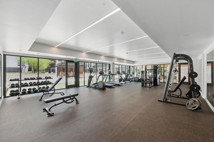 A well-equipped fitness center offers ample space for various exercise routines, featuring full-height glass for abundant light.