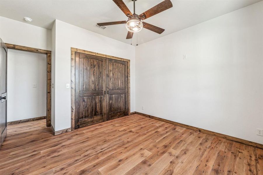 Unfurnished bedroom featuring baseboards, visible vents, a closet, and wood finished floors
