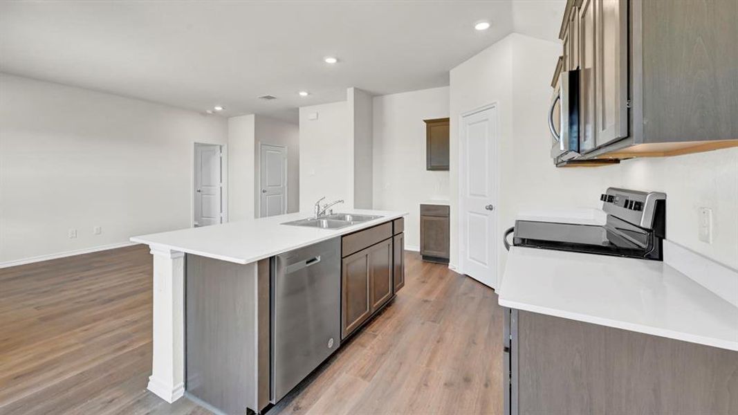 Kitchen island featuring a double basin stainless steel sink, integrated dishwasher, and white countertop