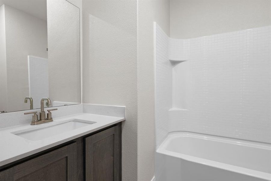 Full bath with vanity, a textured wall, and shower / washtub combination