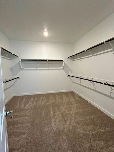Spacious walk-in closet featuring white walls, recessed lighting, and expansive shelving with integrated hanging rods