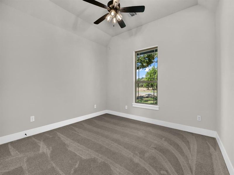 Spare room with dark colored carpet, lofted ceiling, and ceiling fan