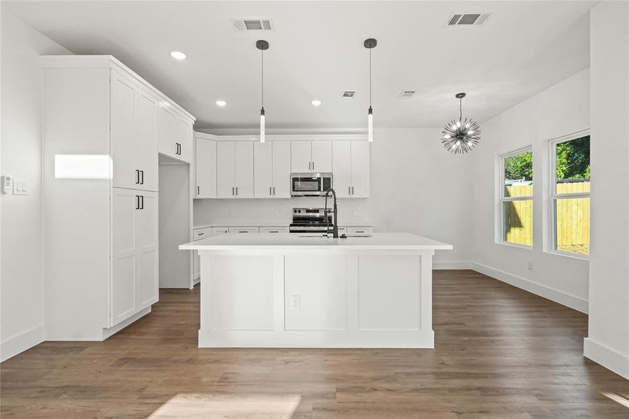 Kitchen with recessed lighting, hanging light fixtures, dark wood-style floors, white cabinetry, and appliances with stainless steel finishes