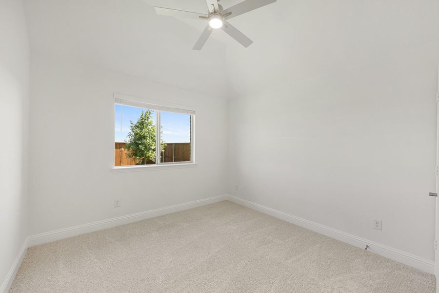 Empty bedroom with vaulted ceiling, ceiling fan, carpet flooring, and a single window