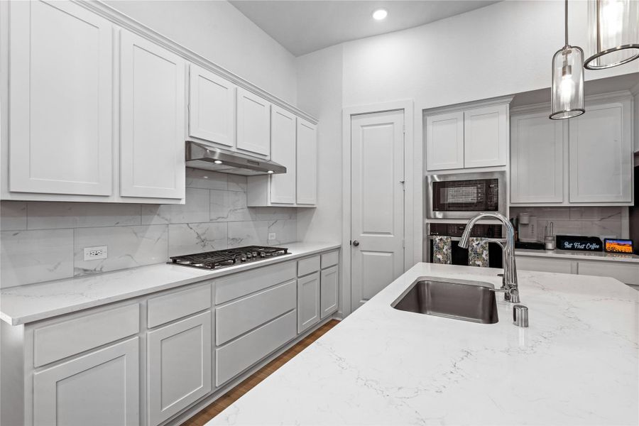 Sleek white cabinetry, modern stainless steel appliances, and elegant marble-style countertops. The spacious layout includes a central island with a sink, perfect for meal preparation and entertaining. Sleek white cabinetry, modern stainless steel appliances, and elegant marble-style countertops. The spacious layout includes a central island with a sink, perfect for meal preparation and entertaining.