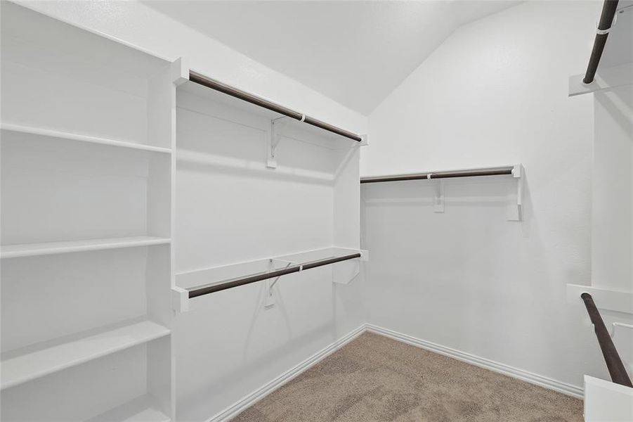 Spacious closet featuring light carpet and lofted ceiling Spacious closet featuring light carpet and lofted ceiling