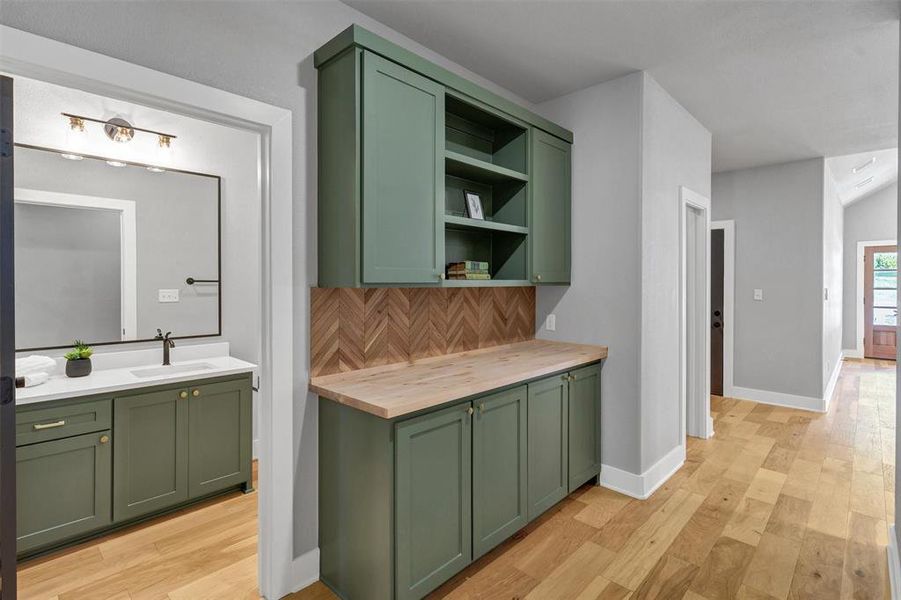 Bar with green cabinetry, wood counters, open shelves, tasteful backsplash, and light wood-style flooring
