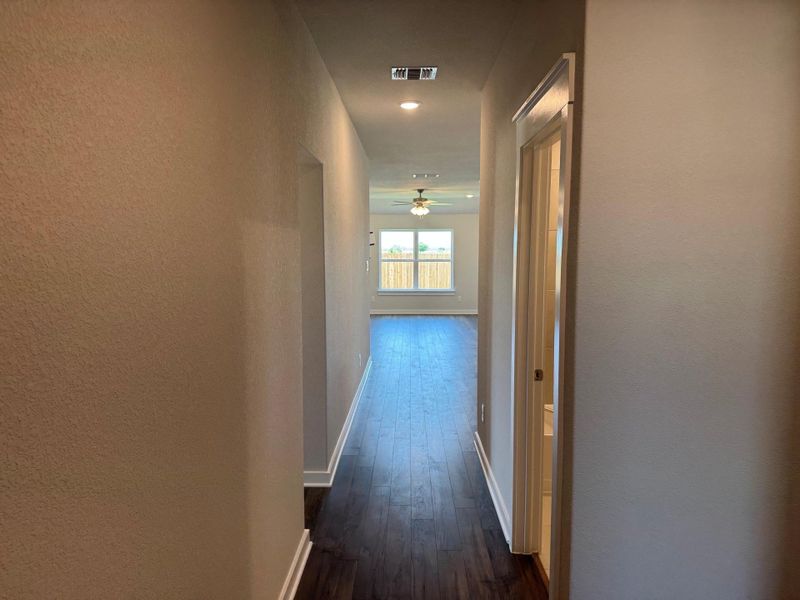 Hallway with dark wood-style flooring and baseboards Hallway with dark wood-style flooring and baseboards