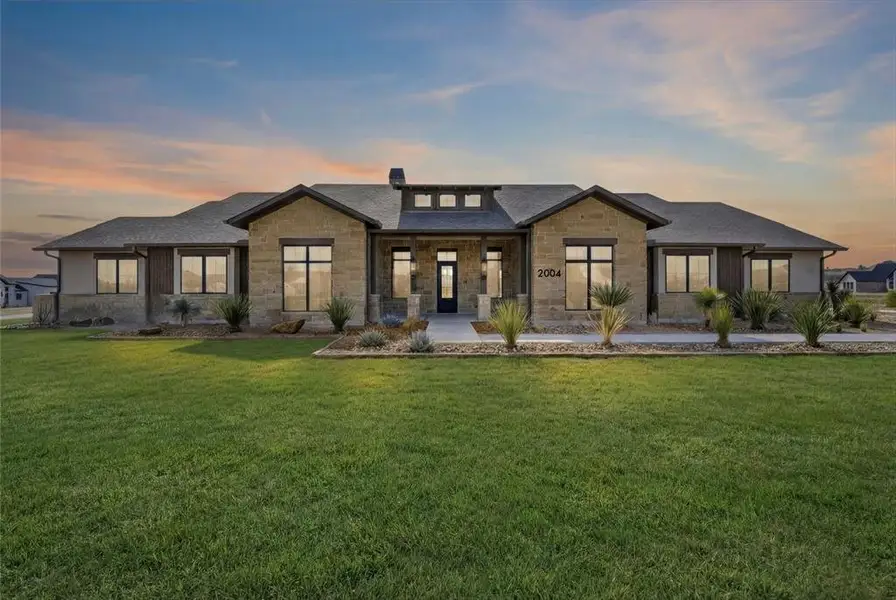 View of front of house with stone siding, a chimney, covered porch, and a front yard View of front of house with stone siding, a chimney, covered porch, and a front yard
