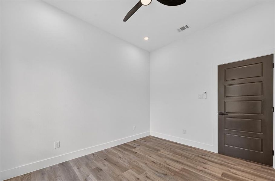 Interior room featuring wood-finish flooring, white walls, and white baseboards Interior room featuring wood-finish flooring, white walls, and white baseboards