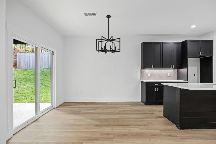 Kitchen with dark cabinets, tasteful backsplash, light wood-style flooring, a chandelier, and recessed lighting