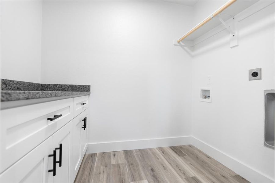 Laundry area with light wood finished floors, washer hookup, cabinet space, and electric dryer hookup