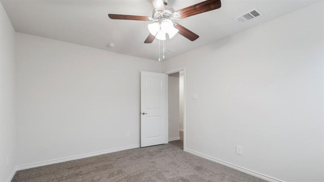 Carpeted empty room with ceiling fan and baseboards Carpeted empty room with ceiling fan and baseboards