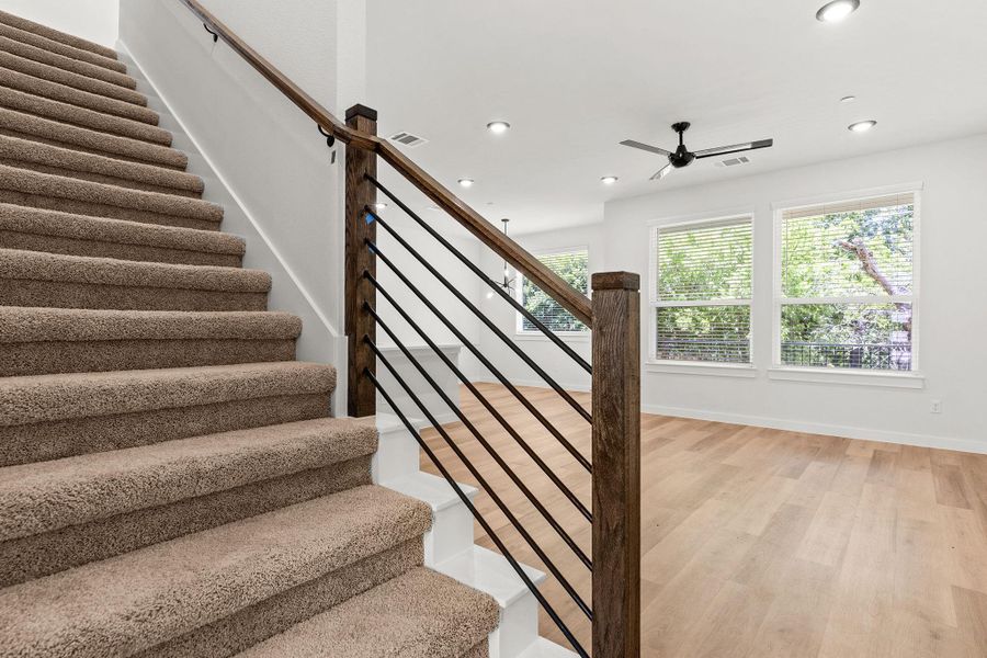 A striking modern staircase with dark wood railings and sleek balusters leads to an open-concept living area. A striking modern staircase with dark wood railings and sleek balusters leads to an open-concept living area.